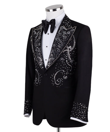 Black embellished three-piece tuxedo with intricate crystal and bead patterns on satin peak lapels, chest, and cuffs. Features a matching vest. Handcrafted luxury suit from BTS Bespoke Istanbul.