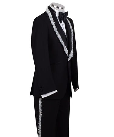 Full front view of a black three-piece tuxedo on a mannequin, featuring heavily hand-embellished shawl lapels with pearls and crystals, and a matching embellishment down the side of the trousers. Includes a black double-breasted vest and a white shirt with a black bow tie (not included).