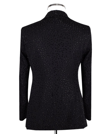 Close-up of a black double-breasted tuxedo jacket on a mannequin, showcasing intricate hand-embellishments with beads and crystals on the lapels and body. Features a peak lapel and black buttons, paired with a white shirt and black bow tie. Front view showing the full jacket and details.