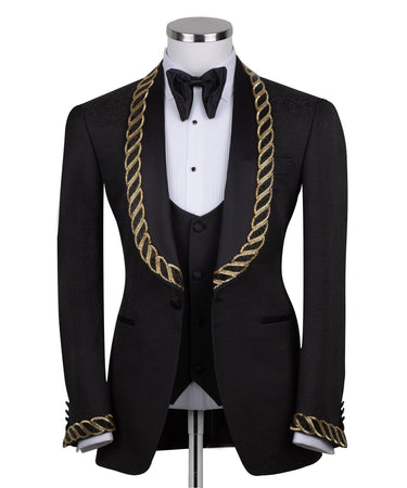 Front view of BTS Bespoke's black jacquard three-piece tuxedo with opulent gold chain embellishments on the shawl lapel and cuffs, tailored in Istanbul. Includes jacket, vest, and trousers.