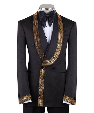 Mannequin wearing a black double-breasted tuxedo with ornate gold beaded peak lapels and matching cuff embellishments, paired with black satin-striped trousers.