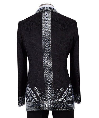 Front view of a black double-breasted tuxedo jacket with extensive silver embellishments, featuring a peak lapel and slim fit design on a mannequin. Back view and close-up showing intricate hand-beading detail.