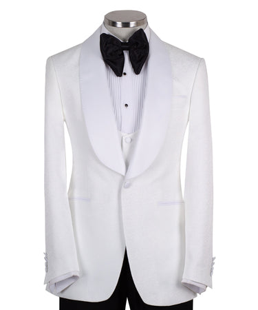 Front view of a white jacquard patterned single-breasted tuxedo jacket with a white satin shawl lapel, displayed on a mannequin. Includes a matching white jacquard vest and black trousers. Handmade in Istanbul luxury bespoke menswear.