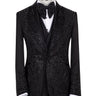 Front view of a black hand-embellished tuxedo with intricate beadwork and sequin patterns, displayed on a mannequin. Features a single-breasted jacket, peak lapel, matching vest, and trousers, embodying luxury bespoke craftsmanship from Istanbul.