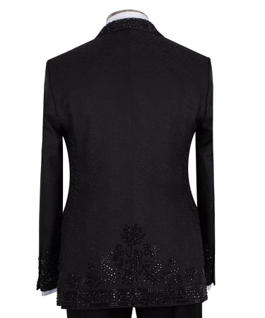 Front view of a black hand-embellished tuxedo with intricate beadwork and sequin patterns, displayed on a mannequin. Features a single-breasted jacket, peak lapel, matching vest, and trousers, embodying luxury bespoke craftsmanship from Istanbul.