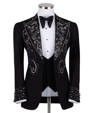 Black embellished three-piece tuxedo with intricate crystal and bead patterns on satin peak lapels, chest, and cuffs. Features a matching vest. Handcrafted luxury suit from BTS Bespoke Istanbul.
