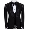 Black three-piece tuxedo on a mannequin, featuring a heavily hand-embellished shawl lapel, shoulders, and sleeves with intricate sparkling beadwork. The tuxedo includes a matching black vest and trousers, designed in a slim fit style, showcasing luxurious craftsmanship from Istanbul.