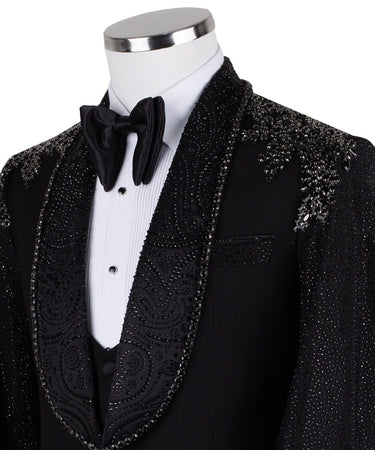 Black three-piece tuxedo on a mannequin, featuring a heavily hand-embellished shawl lapel, shoulders, and sleeves with intricate sparkling beadwork. The tuxedo includes a matching black vest and trousers, designed in a slim fit style, showcasing luxurious craftsmanship from Istanbul.
