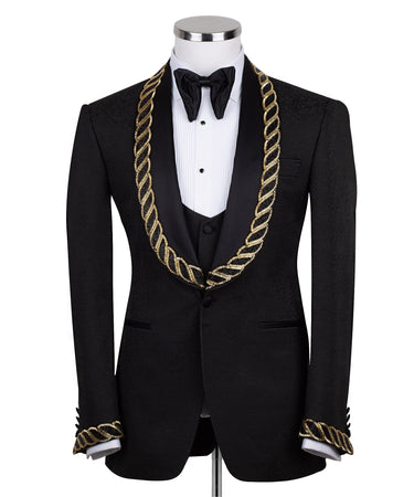 Front view of BTS Bespoke's black jacquard three-piece tuxedo with opulent gold chain embellishments on the shawl lapel and cuffs, tailored in Istanbul. Includes jacket, vest, and trousers.
