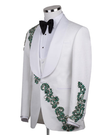 BTS Bespoke white three-piece tuxedo with intricate emerald green hand-embellished details on the jacket, shoulders, and sleeves. Features a white shawl lapel and vest. Front view and side view of the luxury suit on a mannequin.