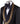 Mannequin wearing a black double-breasted tuxedo with ornate gold beaded peak lapels and matching cuff embellishments, paired with black satin-striped trousers.
