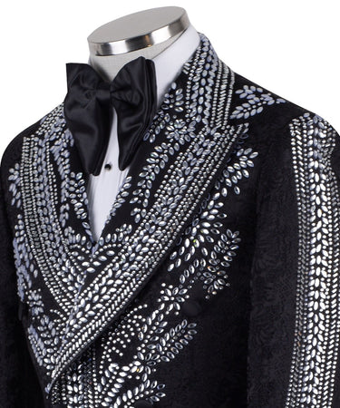 Front view of a black double-breasted tuxedo jacket with extensive silver embellishments, featuring a peak lapel and slim fit design on a mannequin. Back view and close-up showing intricate hand-beading detail.