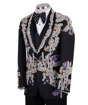Front and side view of a black tuxedo jacket with extensive silver, purple, orange, and blue crystal and gemstone embellishments in floral and baroque patterns, paired with matching black trousers and vest, on a mannequin. Showcases intricate hand-embellished details and luxurious craftsmanship from BTS Bespoke, Istanbul.