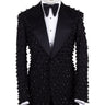 Front view of a black hand-embellished luxury tuxedo jacket with satin peak lapels and matching trousers on a mannequin. Side view close-up of the jacket's intricate black bead embellishments. Close-up of the tuxedo trousers with a satin side stripe and high-waisted detail.