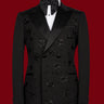 Front view of a black double-breasted tuxedo with satin peak lapels, adorned with intricate black beaded starburst embellishments, worn by a mannequin. The matching trousers with satin side stripe are also shown. This luxurious evening wear is handcrafted in Istanbul by BTS Bespoke.