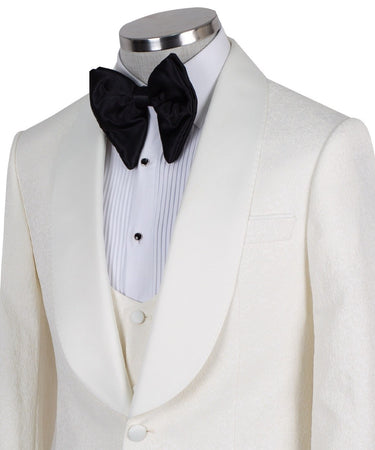 Front view of an ivory jacquard three-piece tuxedo with black trousers on a mannequin. Features a single-breasted jacket with a satin shawl lapel, matching U-neck vest, and subtle floral pattern. Ideal for weddings and formal events.